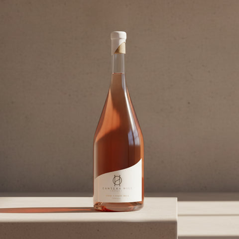 Bottle of rose wine on a wooden surface with a neutral background